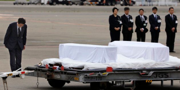 Japanese Foreign Minister Fumio Kishida, left, bows in front of the coffins of the victims who were killed in the last weekend's attack in Bangladeshi capital Dhaka, at Haneda Airport in Tokyo, Tuesday, July 5, 2016. The bodies of the Japanese victims arrived Tuesday morning in Tokyo on a Japanese government airplane. (AP Photo/Shizuo Kambayashi)