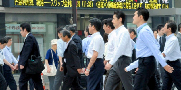 Businessmen cross an intersection, with stock prices seen on an electric market board in Tokyo, Wednesday, June 11, 2008. Japan raised its reading for economic growth in the first quarter, due mainly to a stronger-than-expected increase in capital investment. (AP Photo/Katsumi Kasahara)