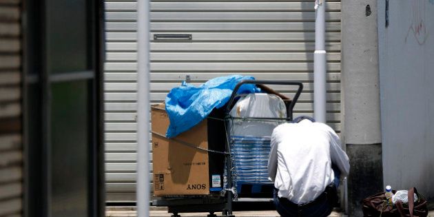 An elderly man squats next to a cart and a bag on a street in Tokyo, Japan, on Monday, July 8, 2013. The number of Japanese seniors living alone will rise 54 percent to 7.17 million in 2030 from 4.66 million in 2010, according to the National Institute of Population and Social Security Research, set up by the Ministry of Health, Labour and Welfare. To manage the costs stemming from the aging society, the government aims to push back the pension age to 65 from 60 in stages through 2025. Photographer: Kiyoshi Ota/Bloomberg via Getty Images