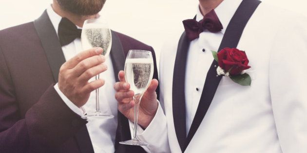 Gay couple celebrating on their wedding day with a glass of champagne