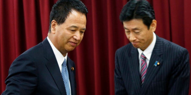 Akira Amari, Japan's minister of state for economic and fiscal policy, left, passes Yasutoshi Nishimura, Japan's deputy minister of state for economic and fiscal policy, during a news conference in Tokyo, Japan, on Thursday, Dec. 5, 2013. Amari said he will take leave for two weeks to receive treatment for early-stage cancer of the tongue. Photographer: Kiyoshi Ota/Bloomberg via Getty Images