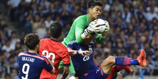 Singapore's goalkeeper Mohamad Izwan Bin Mahbud (top R) makes a save above Japan's defender Tomoaki Makino during the 2018 FIFA World Cup football qualifying match between Japan and Singapore in Saitama on June 16, 2015. The match ended in a 0-0 draw. AFP PHOTO / KAZUHIRO NOGI (Photo credit should read KAZUHIRO NOGI/AFP/Getty Images)