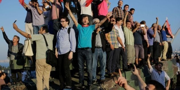 People celebrate on a military tank after they took over military position on the Bosphorus bridge in...