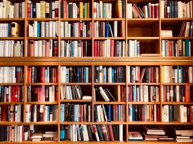 Brown wooden shelfs fully packed with books in a library