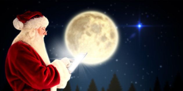 Santa uses a tablet PC against full moon over forest at night
