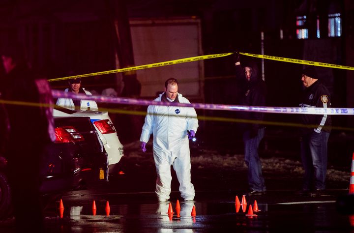 Investigators look over the area after New York City police officers were shot while responding to a robbery at a T-Mobile store in Queens on Tuesday.