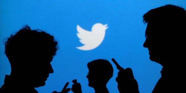 FILE PHOTO: People holding mobile phones are silhouetted against a backdrop projected with the Twitter logo in this illustration picture taken September 27, 2013. REUTERS/Kacper Pempel/Illustration/File Photo