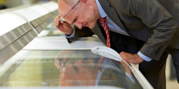 Germany, Cologne, Mature man looking at freezer in supermarket