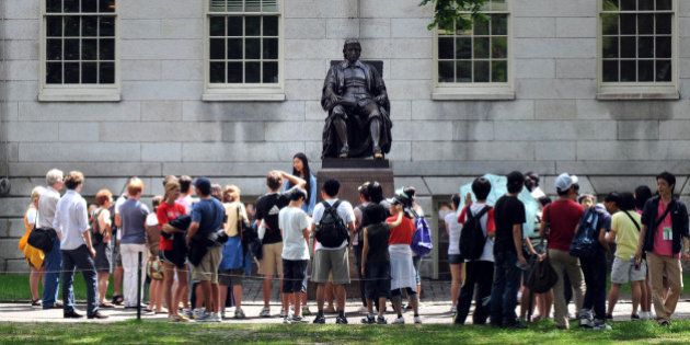 CAMBRIDGE, MA - JULY 30: People touring Harvard Yard stop by the John Harvard statue July 30, 2009 just off Harvard Square in Cambridge, Massachusetts. Harvard Square is a large triangular area located in the heart of Cambridge and adjacent to Harvard University, and is frequented by tens of thousands of tourists a year, and home to thousand of students with MIT University just down the road. (Photo by Darren McCollester/Getty Images)