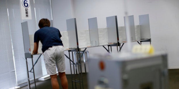 In this July 5, 2016 photo, 18-year-old Fumihiro Yamagishi fills a ballot paper near ballot box at an early voting polling place at Keio University in Yokohama, near Tokyo. The Sunday, July 10âs vote is the first nationwide election since the voting age was lowered to 18 from 20, a step aimed at encouraging voting by younger generations, whose turnout has been extremely low. (AP Photo/Eugene Hoshiko)