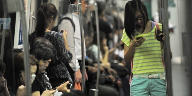 TO GO WITH Lifestyle-Singapore-technology health-telecom-social,FEATURE by Stefanus IanPeople spend their time on smart phone while travelling in the Mass Rapid Transit train in Singapore on April 30, 2014. Alarmed by danger signs among the youth, Singaporeans have begun taking steps to address addiction to the Internet and digital devices, and psychiatrists are pushing for its formal recognition as a disorder in the affluent island nation. AFP PHOTO/ROSLAN RAHMAN (Photo credit should read ROSLAN RAHMAN/AFP/Getty Images)