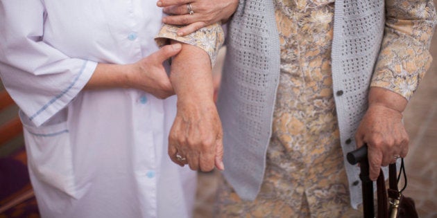 A nursing home nurse, left, guides a resident using a walking stick as they walk through the care home for the elderly in Szklarska Poreba, Poland, on Saturday, Aug. 24, 2013. The Grandma export trend has set hands wringing in Germany, where Munich's leading newspaper denounced it as 'gerontologic colonialism' and compared it to nations exporting their trash. Photographer: Bartek Sadowski/Bloomberg via Getty Images