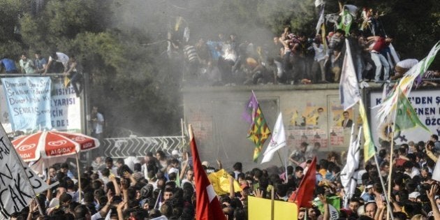 People look at smoke from an explosion which injured several people during a rally by the pro-Kurdish...