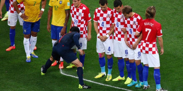 SAO PAULO, BRAZIL - JUNE 12: Referee Yuichi Nishimura sprays a temporary line on the field marking ten yards as players from Brazil and Croatia form a wall during the 2014 FIFA World Cup Brazil Group A match between Brazil and Croatia at Arena de Sao Paulo on June 12, 2014 in Sao Paulo, Brazil. (Photo by Elsa/Getty Images)