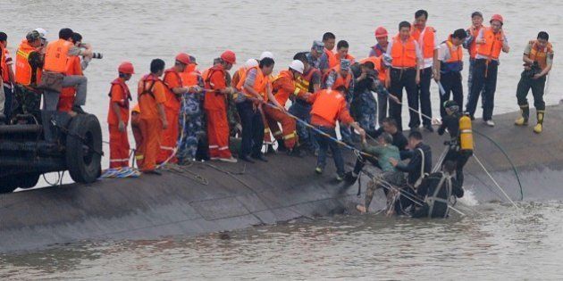 A survivor (C) is rescued by divers from the Dongfangzhixing or 'Eastern Star' vessel which sank in the Yangtze river in Jianli, central China's Hubei province on June 2, 2015. Divers raced to find survivors on June 2 after a Chinese ship sank with more than 450 mainly elderly people in the storm-tossed Yangtze river, raising hopes more people can be found alive. CHINA OUT AFP PHOTO (Photo credit should read STR/AFP/Getty Images)