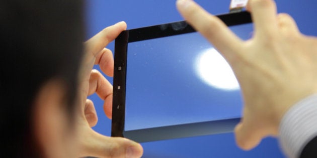 A visitor tries a touch panel screen in the Shenzhen Each Opto-Electronics Co. booth at the Finetech Japan exhibition in Tokyo, Japan, on Wednesday, April 11, 2012. Finetech Japan, the world's largest flat panel display exhibition, will be held through April 13. Photographer: Tomohiro Ohsumi/Bloomberg via Getty Images