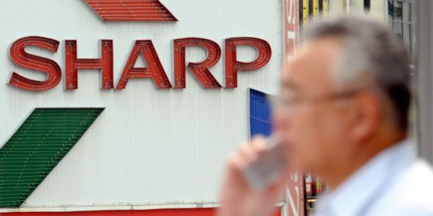 A man speaking on a mobile phone walks by a billboard of Sharp Corp. in Tokyo Thursday, July 31, 2008. Sharp posted a 2.8 percent rise in profit for the fiscal first quarter Thursday as healthy sales of liquid crystal displays for TVs and solar cells helped offset the damage from a strong yen. (AP Photo/Katsumi Kasahara)
