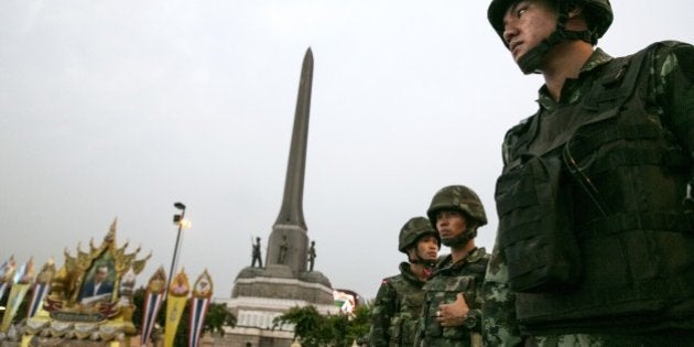 BANGKOK, THAILAND - MAY 26: Thai military stand guard next to portraits honoring Thai King Bhumibol Adulyadej during an anti-coup protests as General Prayuth receives the Royal Endorsement as the military coup leader May 26, 2014 in Bangkok, Thailand. Thailand has seen many months of political unrest and violence which has claimed at least 28 lives. Thailand is known as a country with a very unstable political record, it is now experiencing it's 12th coup with 7 attempted pervious coups. Thailand's coup leaders have detained former Prime Minister Yingluck Shinawatra, along with Cabinet members and other anti-government protest leaders for up to a week. (Photo by Paula Bronstein/Getty Images)