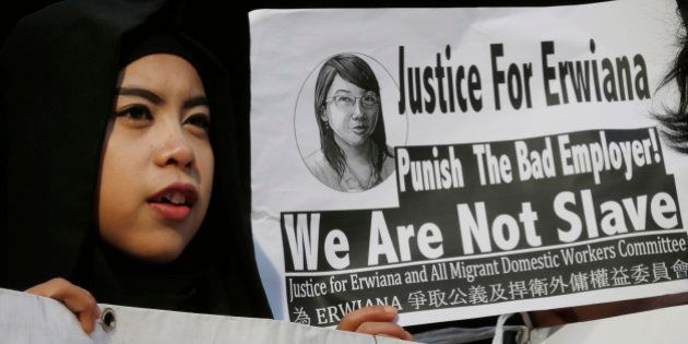 A supporter of Indonesian maid Erwiana Sulistyaningsih, holds a placard as Sulistyaningsih arrives at a court in Hong Kong, Tuesday, Feb. 10, 2015. A Hong Kong woman who was accused of torturing her Indonesian maid in a case that sparked outrage for the scale of its brutality was convicted of a slew of assault and other charges on Tuesday. A judge found Law Wan-tung guilty of 18 charges that also included criminal intimidation and failure to pay wages or give time off work to Sulistyaningsih. (AP Photo/Kin Cheung)