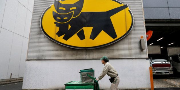 A deliverer of Yamato Transport Co is seen under the company's logo at a business district in Tokyo, Japan, February 9, 2017. Picture taken February 9, 2017. REUTERS/Toru Hanai