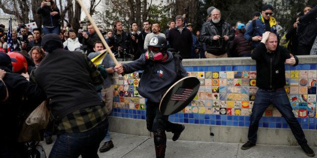 A demonstrator in support of U.S. President Donald Trump swings a stick towards a group of counter-protesters during a