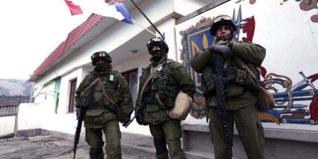 SIMFEROPOL, UKRAINE - MARCH 2: Members of the Russian armed forces stand guard around the Ukrainian military base in the village of Perevalne, 20 km south of Simferopol, on March 2, 2014. Russias armed forces have surrounded Ukraine's troops in the Perevalnoye neighborhood in Ukraine's Autonomous Republic of Crimea, on Sunday. Ukraines military units in Perevalnoye, some 20 km far from Crimeas capital Simferopol, were encircled by more than 200 Russian soldiers. Russia currently has 25 armored vehicles in the region. (Photo by Bulent Doruk/Anadolu Agency/Getty Images)