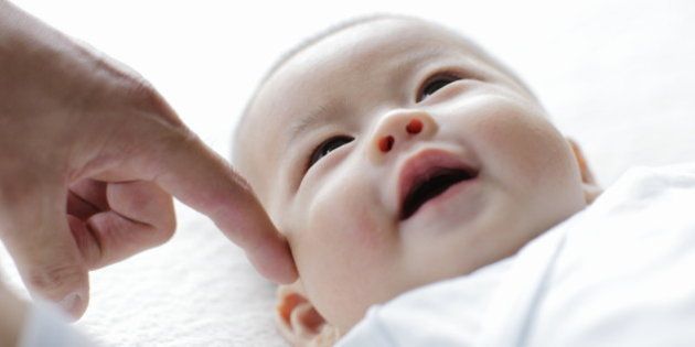Smiling baby with finger of father,close up