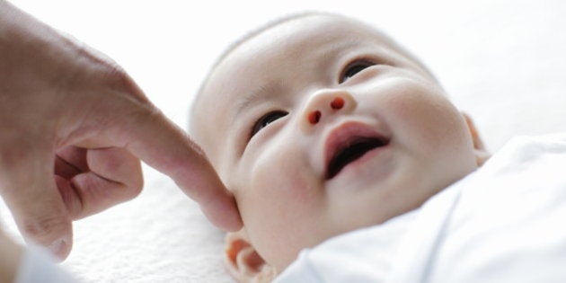 Smiling baby with finger of father,close up