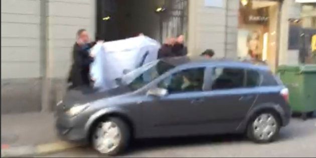 Picture taken from a cell phone video shows hotel employees holding a blanked to hide the identity of a person led out of a side entrance of the Baur au Lac hotel to a waiting car in Zurich, Switzerland, Wednesday, May 27, 2015. Six soccer officials were arrested and detained by Swiss police on Wednesday pending extradition at the request of U.S. authorities after a raid in the luxury hotel. The case involves bribes