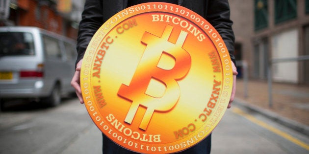 A man poses for a photograph with a mock Bitcoin outside the ANXBTC store, operated by the ANX Bitcoin exchange, in Hong Kong, China, on Friday, Feb. 28, 2014. ANX, a Hong Kong-based platform for trading virtual currencies, opened the first retail store in the city that allows individuals to buy and sell Bitcoins in Hong Kong dollars. Photographer: Brent Lewin/Bloomberg via Getty Images