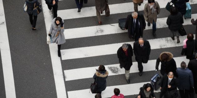 Pedestrians cross a road in Tokyo, Japan, on Friday, Feb. 24, 2017. Japan is responding to a government campaign to get the country's chronically overworked populace to leave the office by 3 p.m. on the last Friday of every month and go spend some cash. They call it Premium Friday. Photographer: Akio Kon/Bloomberg via Getty Images