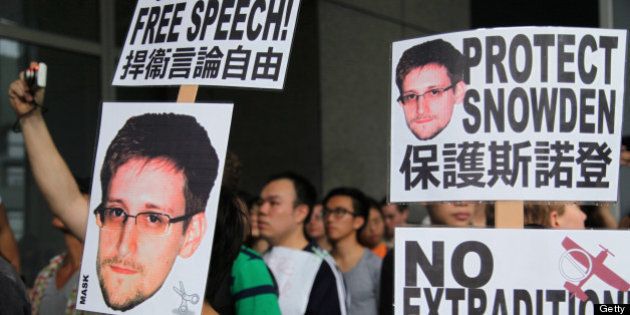 Protesters hold placards outside government headquarters during a rally in support of Edward Snowden, the former National Security Agency contractor, in Hong Kong, China, on Saturday, June 15, 2013. Protesters marched to Hong Kongs government headquarters demanding their leaders protect Edward Snowden, who fled to the city after exposing a U.S. surveillance program. Photographer: Luke Casey/Bloomberg via Getty Images