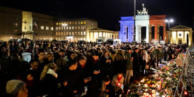 With the Brandenburg Gate, illuminated in the French national colors, in the background, people lay down flowers and light candles for the victims killed in the Friday's attacks in Paris, France, in front of the French Embassy in Berlin, Saturday, Nov. 14, 2015. French President Francois Hollande said more than 120 people died Friday night in shootings at Paris cafes, suicide bombings near France's national stadium and a hostage-taking slaughter inside a concert hall. (AP Photo/Markus Schreiber)
