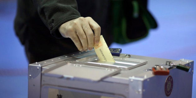 A man casts his vote for parliament's lower house election at a polling station in Tokyo, Sunday, Dec. 14, 2014. Japanese voters headed to the polls Sunday in a parliamentary election that is expected to reaffirm the ruling Liberal Democratic Party's majority, though many analysts were predicting a record low turnout. (AP Photo/Eugene Hoshiko)