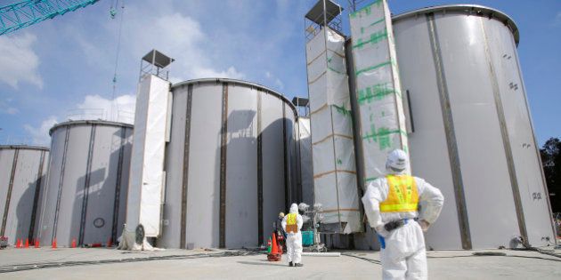 A worker wearing a protective suit and mask looks at storage tanks for radioactive water under construction in the J-1 area at Tokyo Electric Power Co.'s (Tepco) Fukushima Dai-Ichi nuclear power plant in Fukushima, Japan, on Monday, March 10, 2014. Tepco's Fukushima Dai-Ichi plant had three reactor core meltdowns after it was hit by an earthquake and tsunami on March 11, 2011. Photographer: Toru Hanai/Pool via Bloomberg