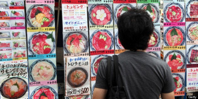 A man looks at menu items displayed outside a Japanese restaurant in Tokyo, Japan, on Monday, June 25, 2012. Japanese lawmakers will vote on a consumption tax increase on June 26. Photographer: Haruyoshi Yamaguchi/Bloomberg via Getty Images