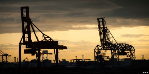 Cargo cranes are silhouetted against a golden sky at the Osaka harbor and shipping complex in Japan.