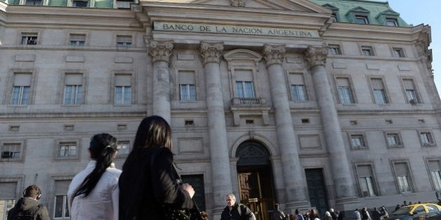 People walk by the Bank of the Nation headquarters in front of Plaza de Mayo square in Buenos Aires on July 30, 2014. Last-ditch talks aimed at averting Argentina's second default in 13 years were to resume Wednesday in New York, after Tuesday's marathon session failed to reach a deal. AFP PHOTO / Daniel GARCIA (Photo credit should read DANIEL GARCIA/AFP/Getty Images)