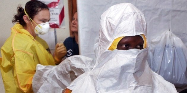 A picture taken on July 24, 2014 shows staff of the Christian charity Samaritan's Purse putting on protective gear in the ELWA hospital in the Liberian capital Monrovia. An American doctor battling West Africa's Ebola epidemic has himself fallen sick with the disease in Liberia, Samaritan's Purse said on July 27. AFP PHOTO / ZOOM DOSSO (Photo credit should read ZOOM DOSSO/AFP/Getty Images)