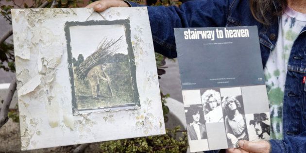 A Led Zeppelin fan holds up an album and sheet music for 'Stairway to Heaven' outside of federal court in Los Angeles, California, U.S., on Tuesday, June 14, 2016. Jimmy Page and Robert Plant, two of Led Zeppelin's founder members, arrived in court today to defend themselves against accusations that Stairway to Heaven, the bands most famous song, was plagiarized. Photographer: Patrick T. Fallon/Bloomberg via Getty Images