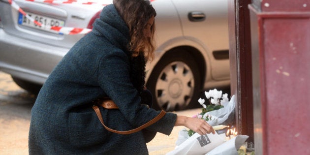 PARIS, FRANCE - NOVEMBER 14: A woman lights a candle outside Le Carillon bar, the day after a deadly attack on November 14, 2015 in Paris, France. At least 120 people have been killed and over 200 injured, 80 of which seriously, following a series of terrorist attacks in the French capital. (Photo by Antoine Antoniol/Getty Images)