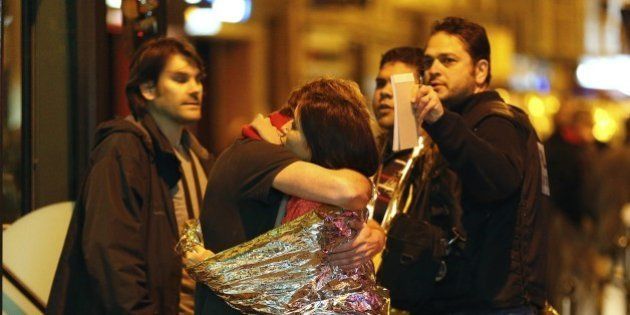 People hug each other before being evacuated by bus, near the Bataclan concert hall in central Paris, on November 14, 2015. More than 100 people were killed in a mass hostage-taking at a Paris concert hall on November 13 and many more were feared dead in a series of bombings and shootings, as France declared a national state of emergency. AFP PHOTO / FRANCOIS GUILLOT (Photo credit should read FRANCOIS GUILLOT/AFP/Getty Images)
