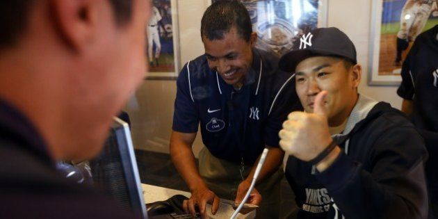 NEW YORK, NY - AUGUST 06: Pitcher Masahiro Tanaka #19 of the New York Yankees helps sell tickets in the advance ticket window before the start of their game against the Detroit Tigers at Yankee Stadium on August 6, 2014 in the Bronx borough of New York City. (Photo by Rich Schultz/Getty Images)