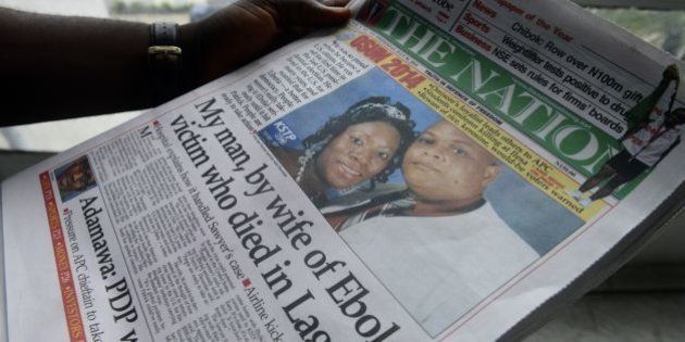 A man reads a newspaper featuring a front page story on the death of Liberian diplomat Patrick Sawyer (pictured with his wife Decontee) who died of the Ebloa virus in Lagos on July 30, 2014. Nigeria is on alert against the possible spread of Ebola after the first confirmed death from the virus in Lagos, Africa's biggest city and the country's financial capital. The victim, who worked for the Liberian government, collapsed at Lagos international airport after arriving on a flight from Monrovia via the Togolese capital Lome, according to the Nigerian government. Doctors Without Borders (MSF) warned that the crisis gripping Guinea, Liberia and Sierra Leone would only get worse and could not rule out it spreading to other countries. AFP PHOTO/PIUS UTOMI EKPEI (Photo credit should read PIUS UTOMI EKPEI/AFP/Getty Images)