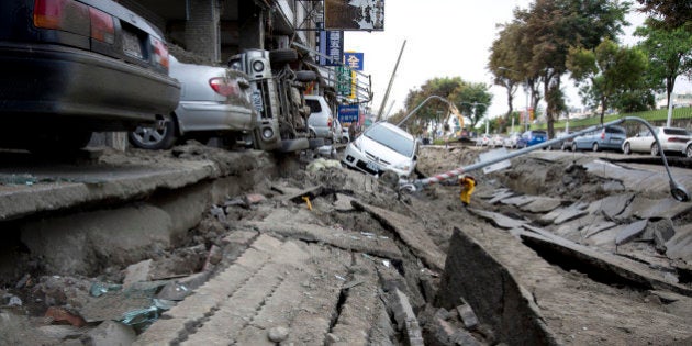 KAOHSIUNG, TAIWAN - AUGUST 01: Vehicles lie on the damaged road after gas explosions in southern Kaohsiung on August 1, 2014 in Kaohsiung, Taiwan. A series of powerful gas blasts killed 25 people and injured up to 267 in the southern Taiwanese city of Kaohsiung, overturning cars and ripping up roads, officials said. (Photo by Ashley Pon/Getty Images)