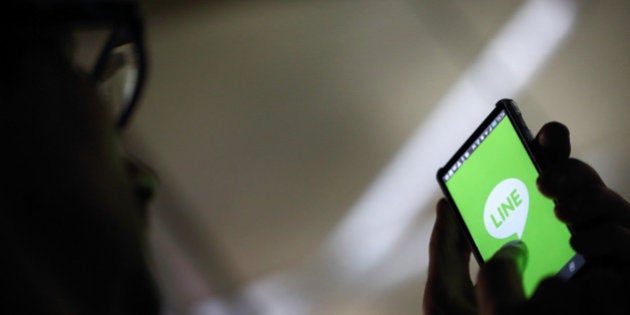 A man uses a smartphone displaying the logo of Line Corp., controlled by Naver Corp., in this arranged photograph in Tokyo, Japan, on Friday, July 18, 2014. Line, operator of Japan's most popular mobile messaging service, filed confidentially for an initial offering in the U.S., people with knowledge of the matter said, taking a step closer to a dual-listing in New York and Tokyo. Photographer: Tomohiro Ohsumi/Bloomberg via Getty Imagesg