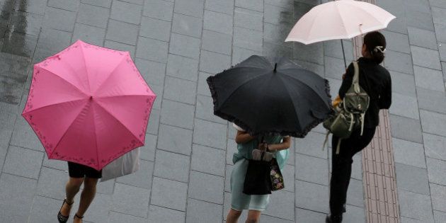 HIMEJI, JAPAN - AUGUST 10: Women walk through strong rain and wind delivered by Typhoon Halong on August 10, 2014 in Himeji, Japan. The Japan Meteorological Agency has issued heavy rain and wind warnings. More than one million people have been advised to evacuate areas across of South-Western Japan. (Photo by Buddhika Weerasinghe/Getty Images)