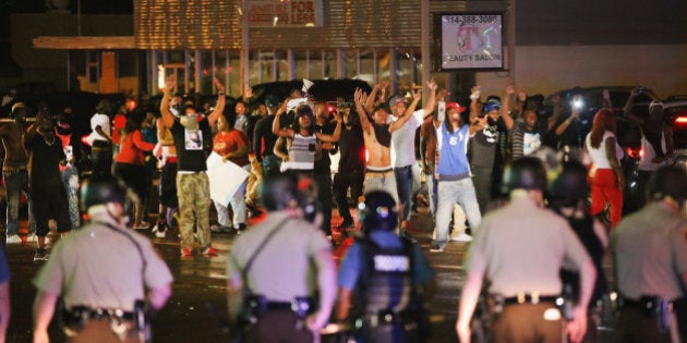 FERGUSON, MO - AUGUST 15: Demonstrators taunt police during a protest over the shooting death of Michael Williams on August 15, 2014 in Ferguson, Missouri, Police shot pepper spray, smoke, gas and flash grenades at protestors before retreating. Several businesses were looted as the county police sat nearby with armored personnel carriers (APC). Violent outbreaks have taken place in Ferguson since the shooting death of Brown by a Ferguson police officer on August 9. (Photo by Scott Olson/Getty Images)