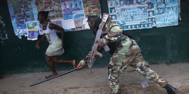 MONROVIA, LIBERIA - AUGUST 20: A Liberian Army soldier, part of the Ebola Task Force, beats a local resident while enforcing a quarantine on the West Point slum on August 20, 2014 in Monrovia, Liberia. The government ordered the quarantine of West Point, a congested seaside slum of 75,000, on Wednesday, in an effort to stop the spread of the virus in the capital city. Liberian soldiers were also sent in to the seaside favela to extract West Point Commissioner Miata Flowers and her family members after residents blamed the government for setting up a holding center for suspected Ebola patients to be set up in their community. A mob overran and closed the facility on August 16. The military also began enforcing a quarrantine on West Point, a congested slum of 75,000, fearing a spread of the epidemic. The Ebola virus has killed more than 1,200 people in four African nations, more in Liberia than any other country. (Photo by John Moore/Getty Images)