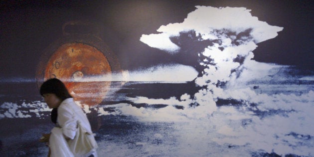 HIROSHIMA, JAPAN - AUGUST 5: A visitor passes by a wall displaying a picture of the mushroom cloud pictured when the atomic bomb was dropped on August 5, 2004 in Hiroshima, Japan. Tomorrow Hiroshima will mark the 59th anniversary of the dropping of the first atomic bomb in Hiroshima at the Hiroshima Peace Memorial Park. (Photo by Junko Kimura/Getty Images)